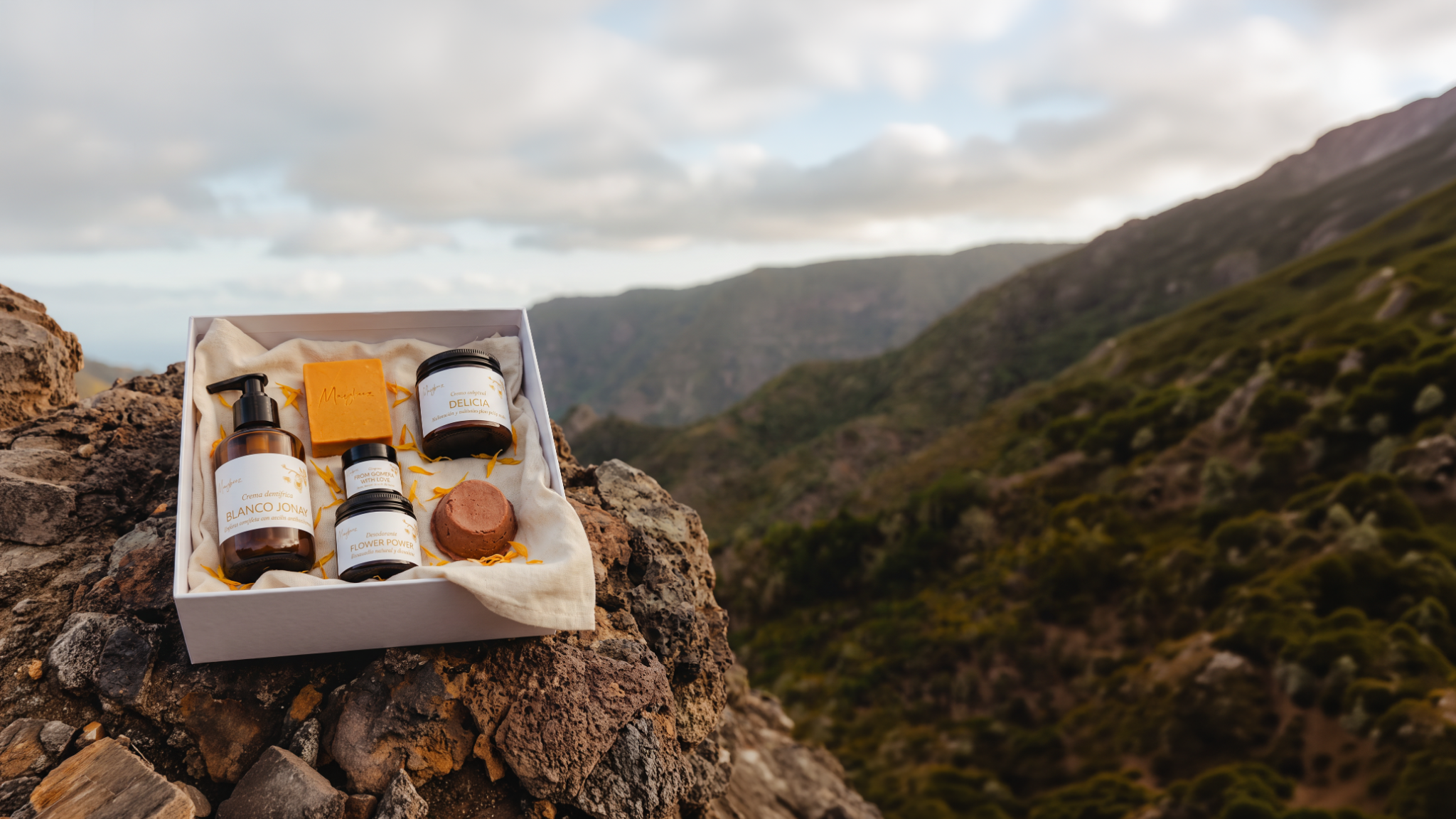 Cesta de productos MayBeez sobre piedra, ante un paisaje de La Gomera